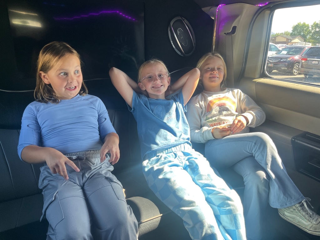 Farr West Elementary students posing excitedly by a limo for their prize ride, celebrating their excellent behavior and Blue Leader Bar achievement.