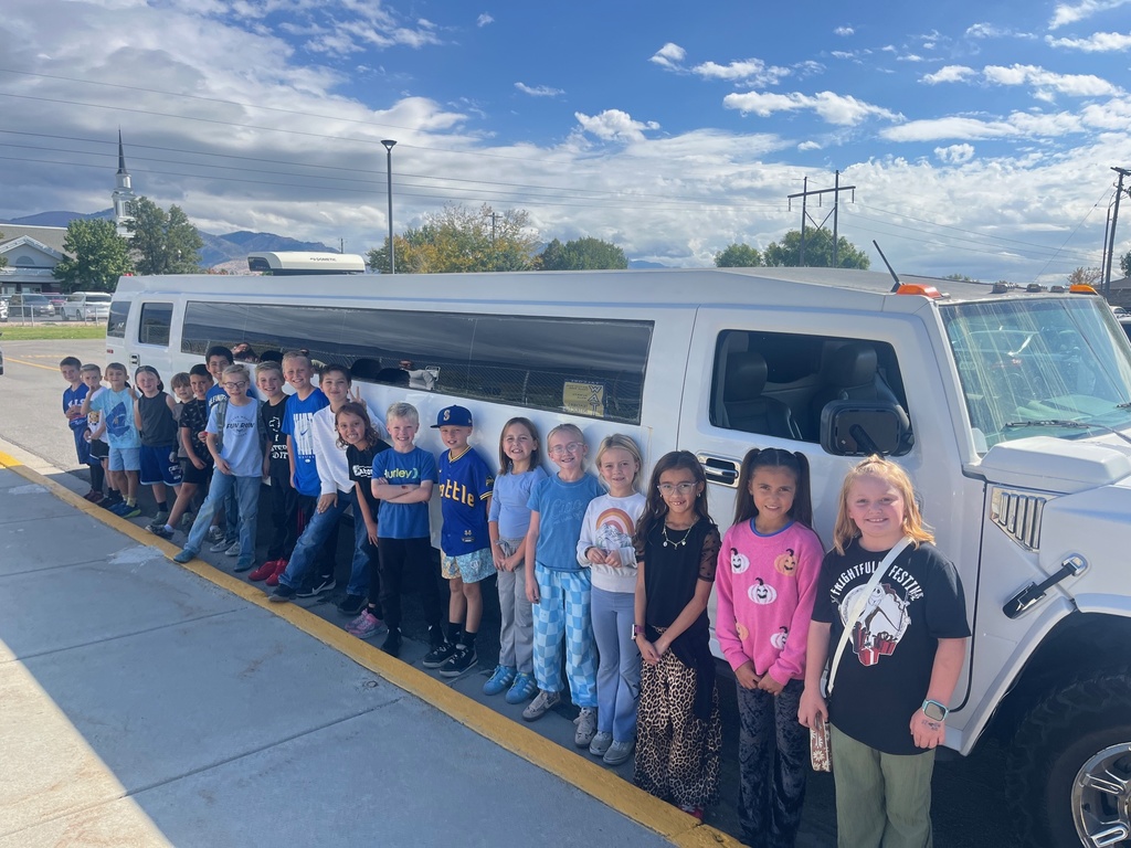 Farr West Elementary students posing excitedly by a limo for their prize ride, celebrating their excellent behavior and Blue Leader Bar achievement.