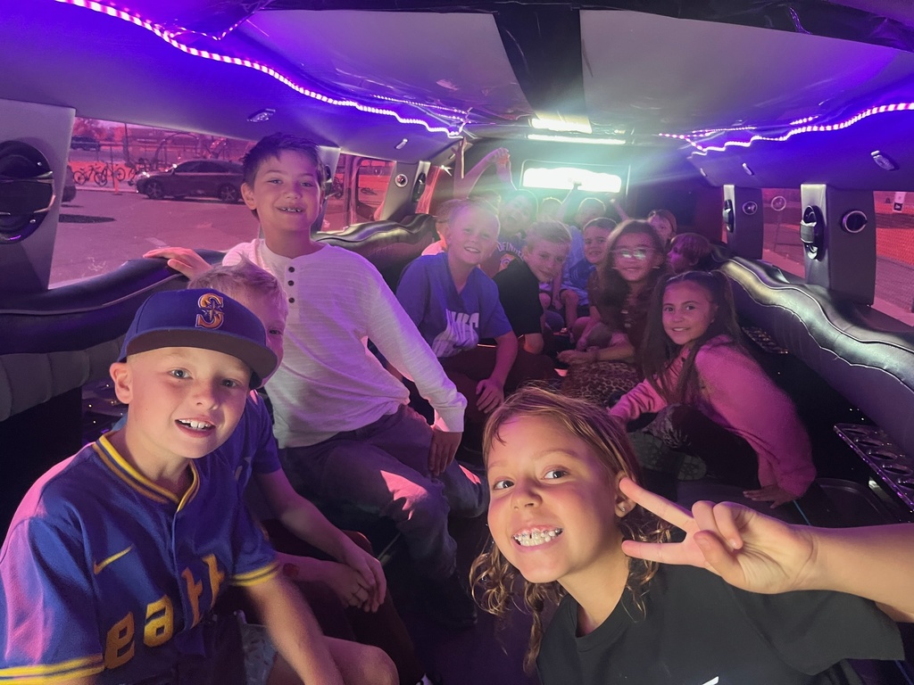 Farr West Elementary students posing excitedly by a limo for their prize ride, celebrating their excellent behavior and Blue Leader Bar achievement.