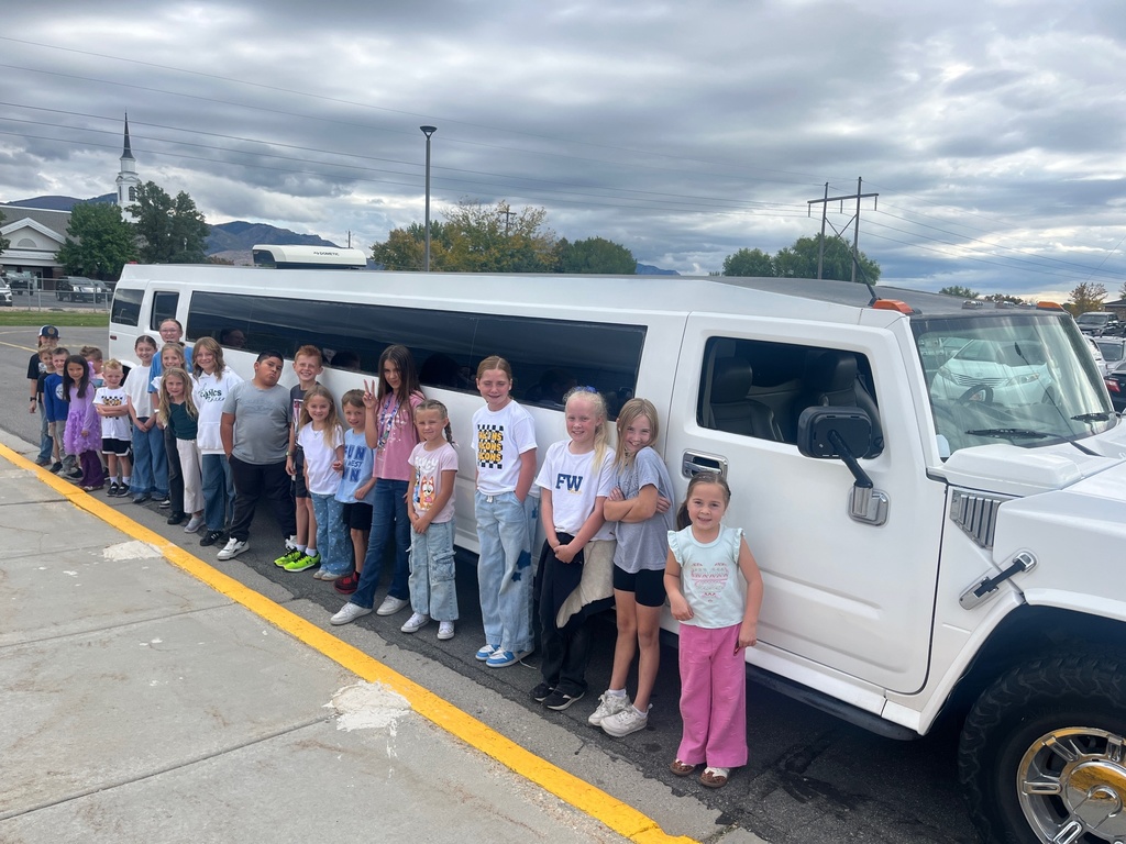 Farr West Elementary students posing excitedly by a limo for their prize ride, celebrating their excellent behavior and Blue Leader Bar achievement.