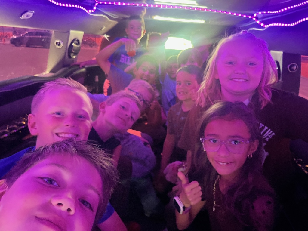 Farr West Elementary students posing excitedly by a limo for their prize ride, celebrating their excellent behavior and Blue Leader Bar achievement.
