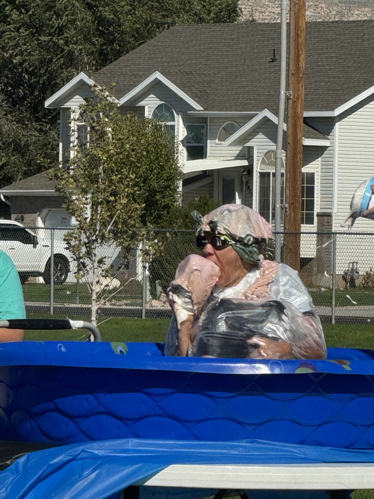 mrs elliott sitting in blue swimming pool getting ice cream, whipped cream, and chocolate fudge dumped on her