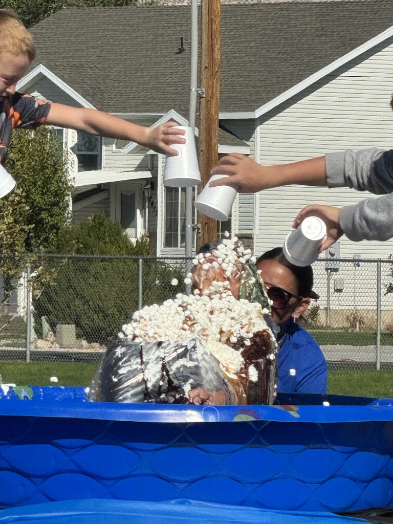 mrs elliott sitting in blue swimming pool getting ice cream, whipped cream, and chocolate fudge dumped on her