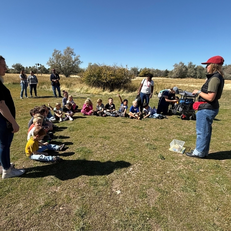 students in field listening to teacher