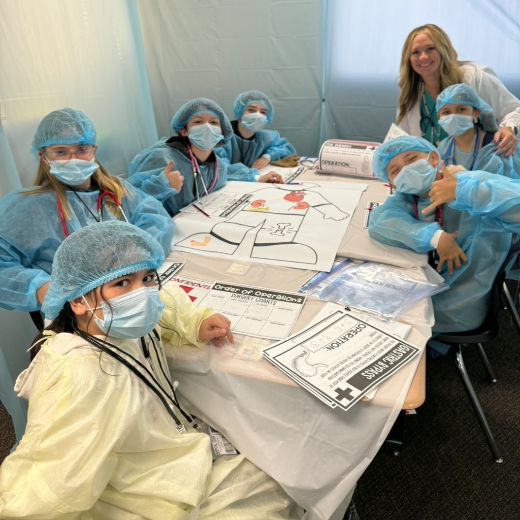 Kids dressed like surgeons working on a project at a table