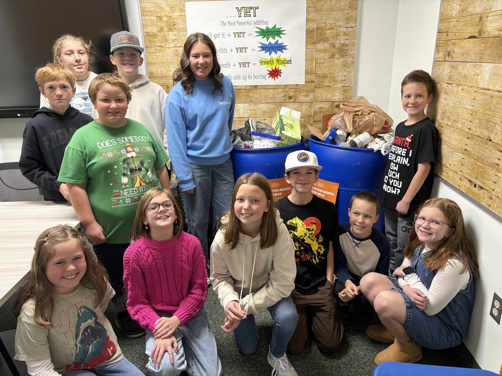 Students posing for camera in front of food for our food drive