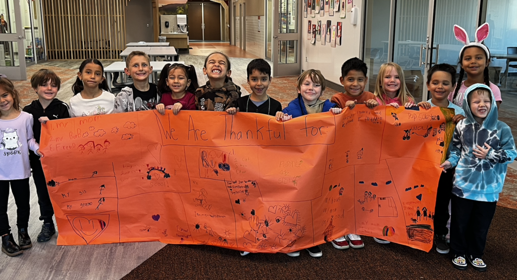 students standing together holding a banner that they created stating what they are thankful for.