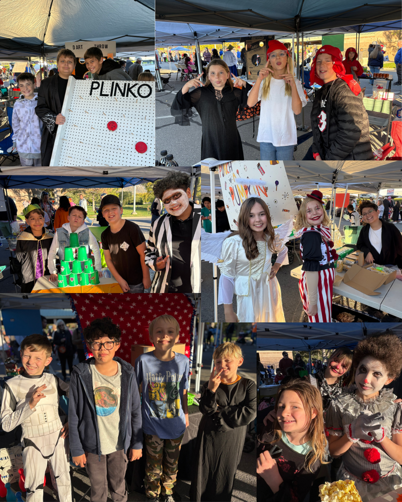 Kids in costumes in front of their carnival booth posing for the camera