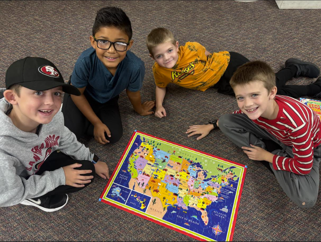 Four boys around a puzzle of the U.S.A map.