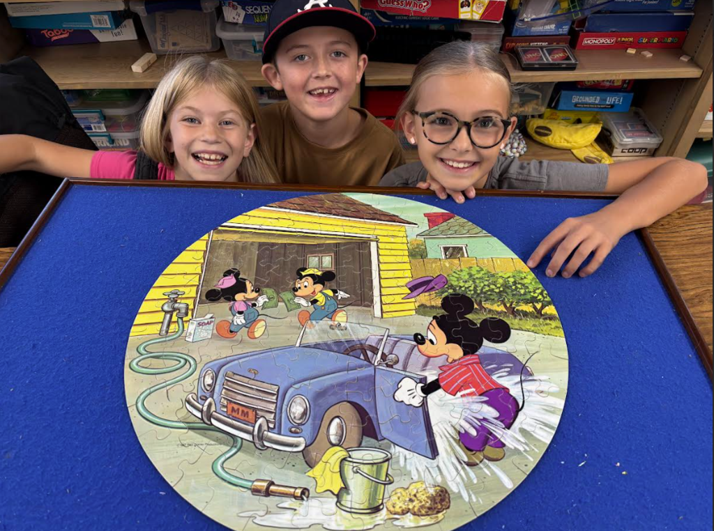Three Students around a Mickey Mouse puzzle.