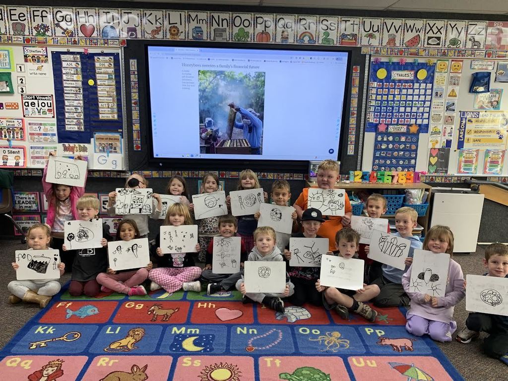 Students hold up their artwork. 
