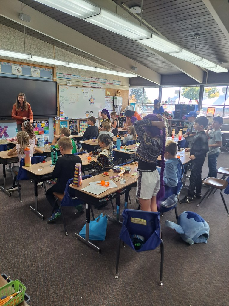 A collection of photos showing elementary students in various Halloween costumes participating in classroom parties. The images include students doing art projects, making snacks, drinking punch, and playing games with their teachers and parent volunteers.