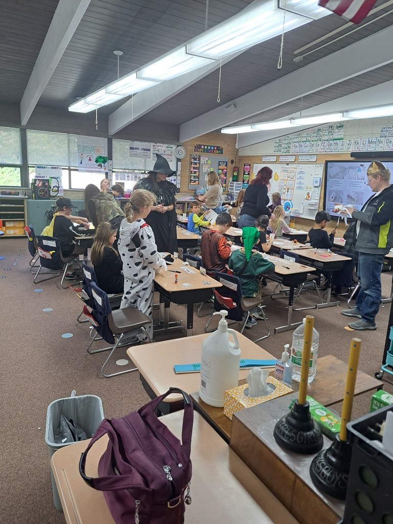 A collection of photos showing elementary students in various Halloween costumes participating in classroom parties. The images include students doing art projects, making snacks, drinking punch, and playing games with their teachers and parent volunteers.