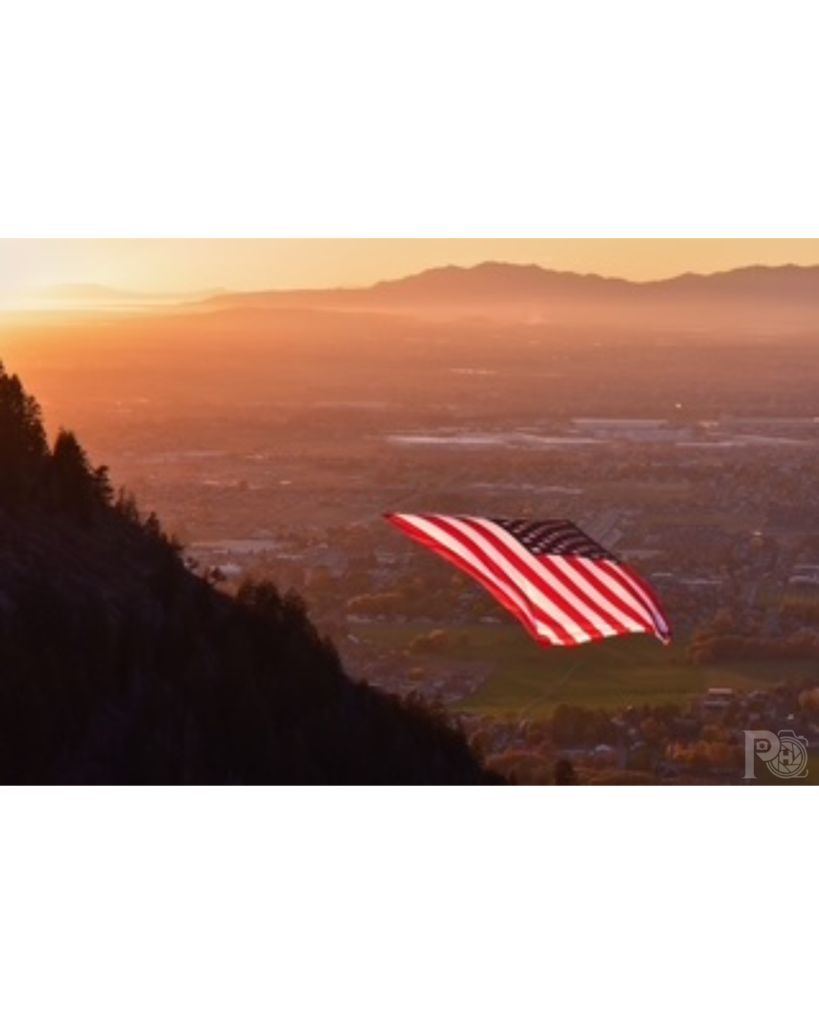 Photo of the American Flag "The Major" hanging in the Coldwater Canyon with North Ogden City below at sunset.