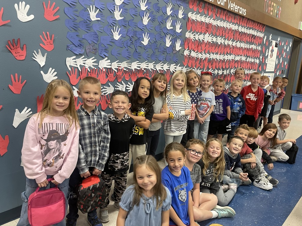 1st graders in front of American flag made of handprints