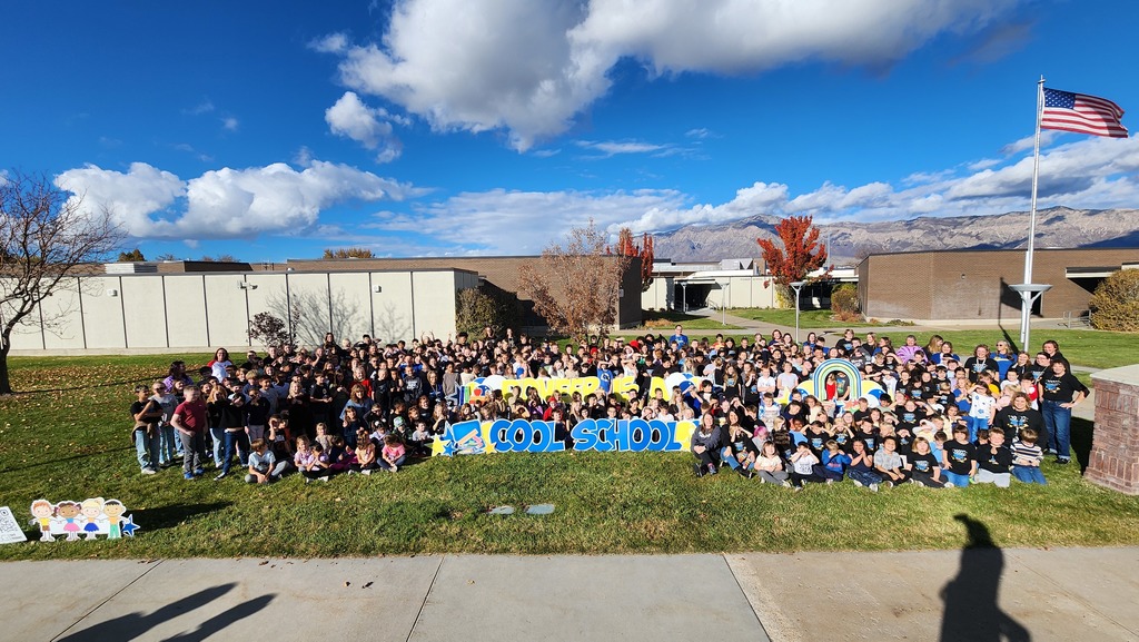 Kids and Teacher pose in front of school for the camera.