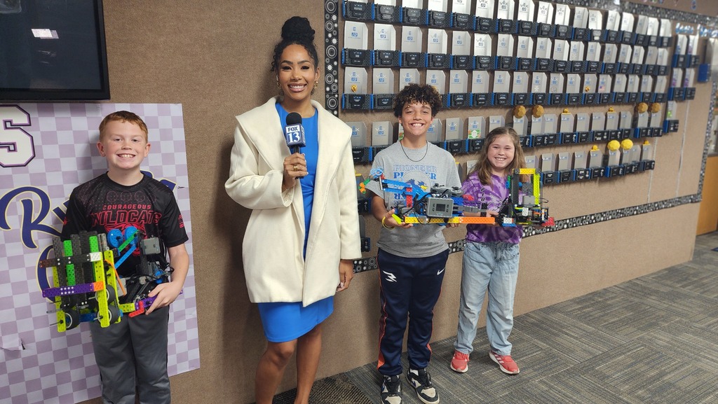 Students with robots posing for camera with reporter