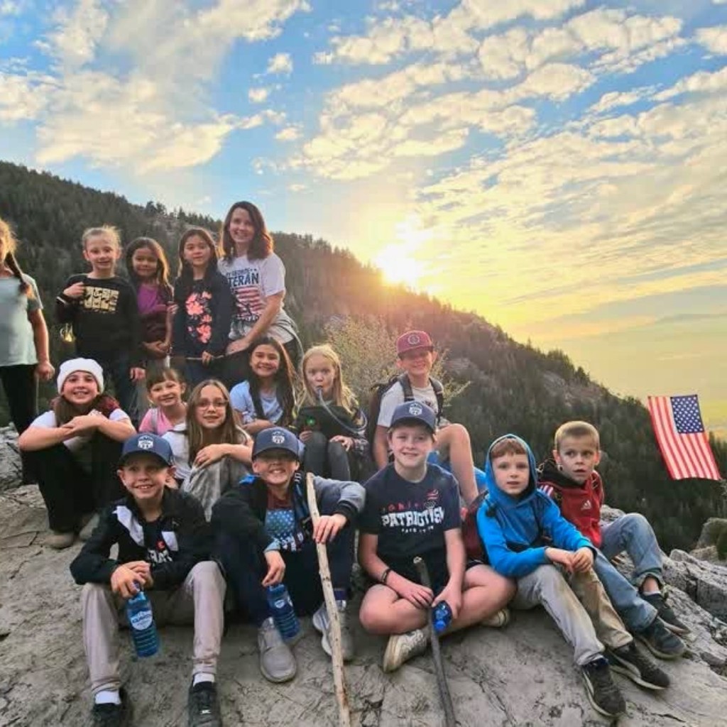 A group of kids at the top of a mountain over looking the flag (The Major)