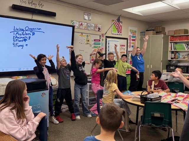 Kids standing in front of the class acting out Living organisms.