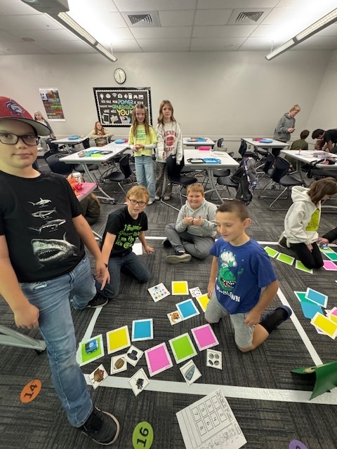 kids gathered on the floor doing some activity with pictures and colored cards on the floor