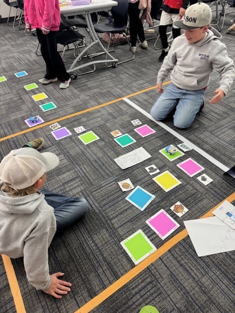 students playing a game with pictures and color squares on the ground