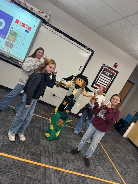 students gathered around a scare crow with cup phones smiling