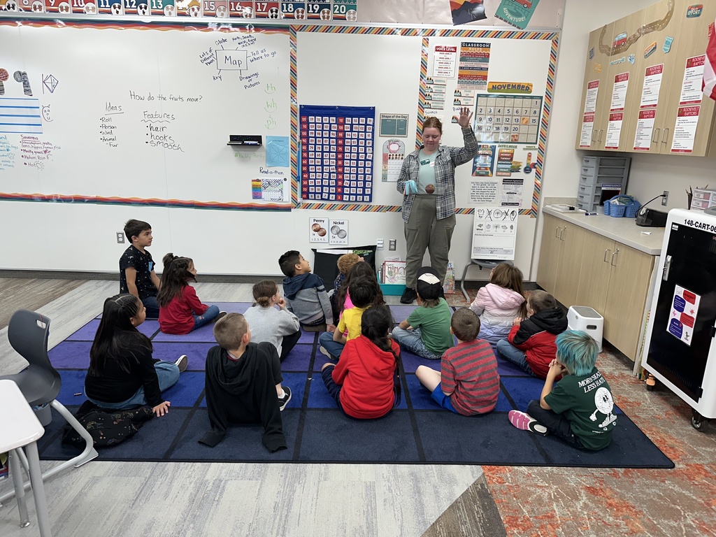 a class of first graders watching an experiment with an apple that the teacher is dropping
