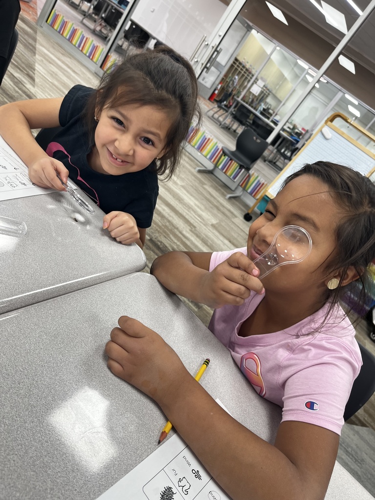 two girls looking through magnifying glasses and smiling