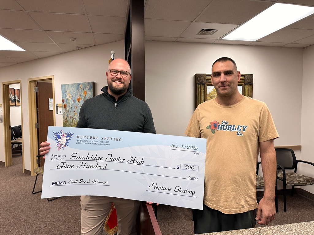Picture of principal at SRJH & Owner of Neptune skae with a check we won