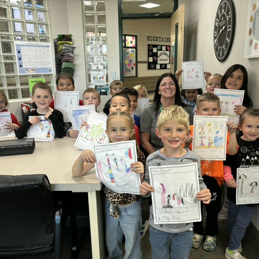 Kids holding gratitude pictures, posing with Mrs. Jacobsen