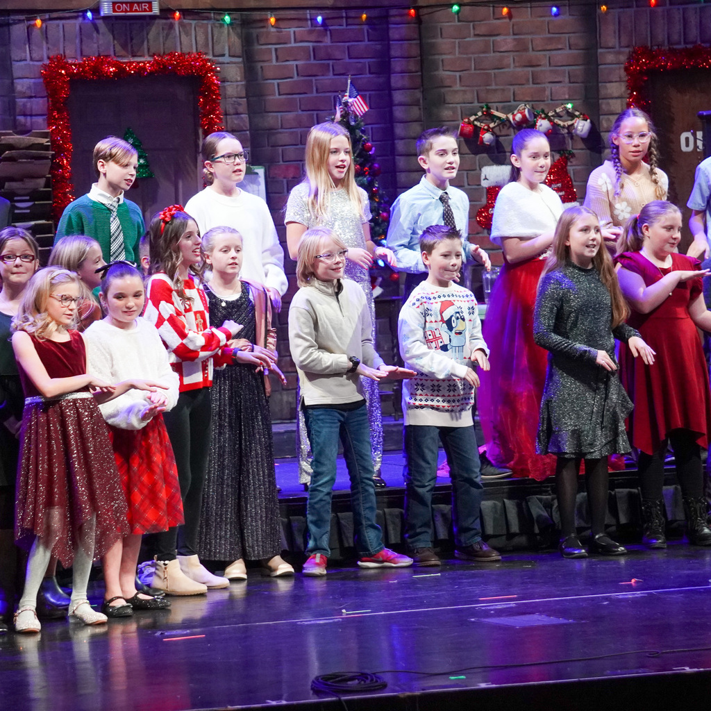 Well dressed children are singing on stage