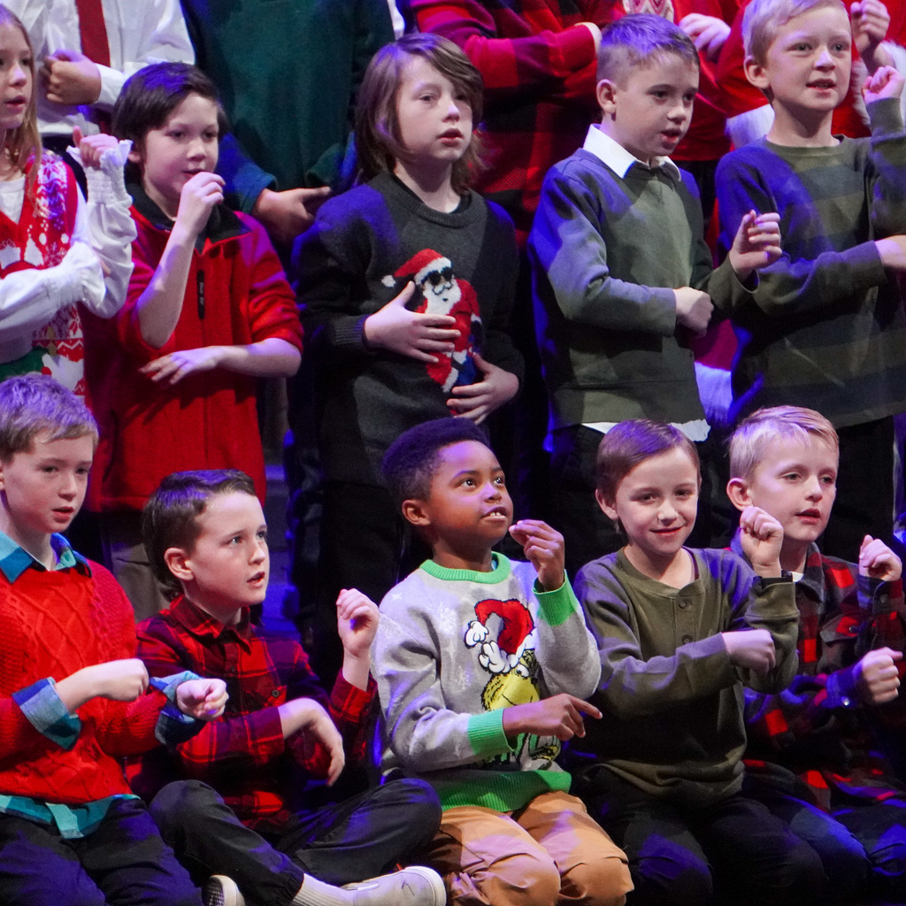 Multiple children are signing on a stage