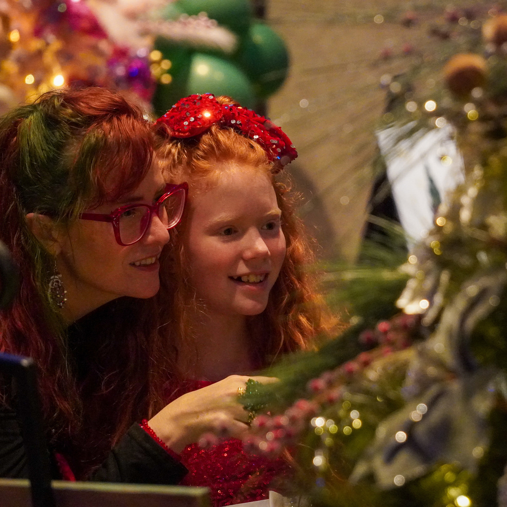 A young girl with her mother looks at a Christmas Tree