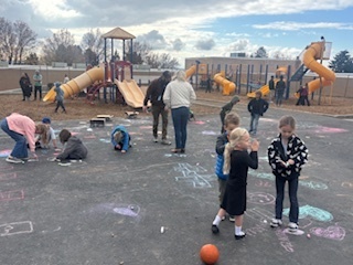 Students out at lunch recess drawing with chalk on the black top with  Rad Dads.