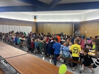 Students eating lunch in the lunchroom with Rad Dads.