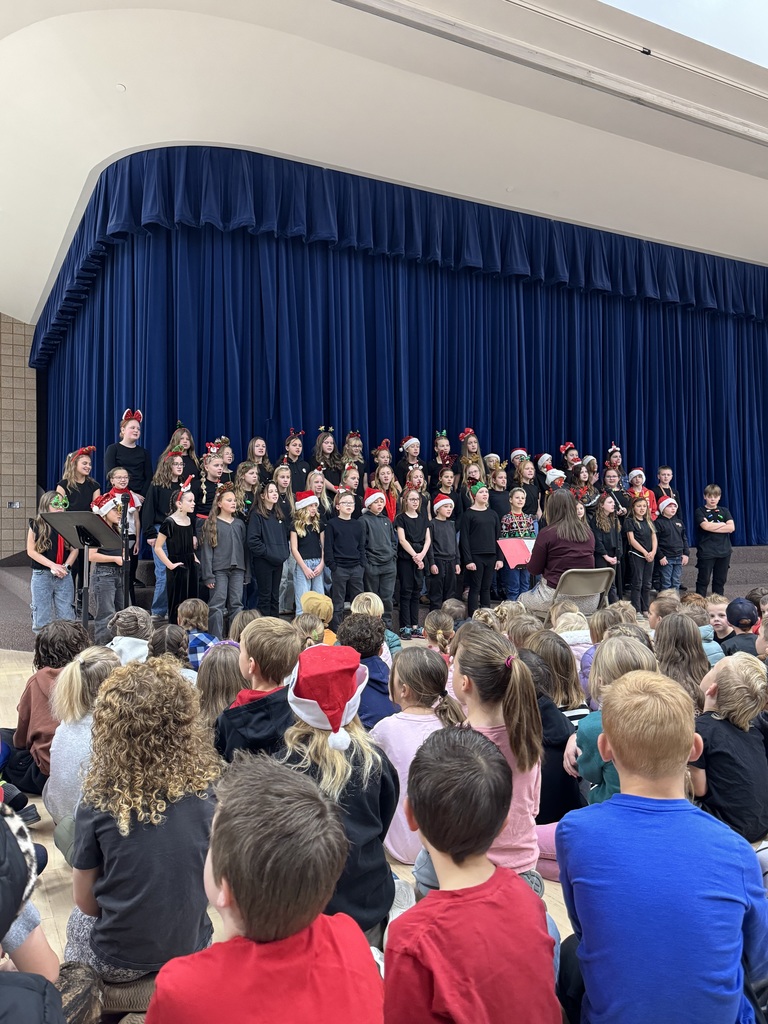 students sitting on the ground watching choir students sing