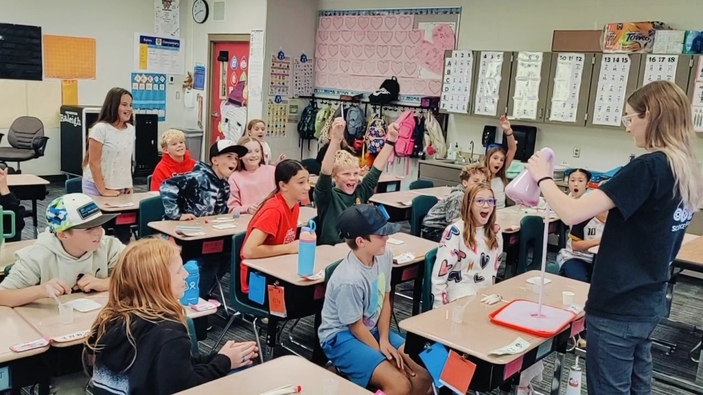 Fifth grade students sitting at their desks in their desks watching and experiment done by Discovery Gateway.