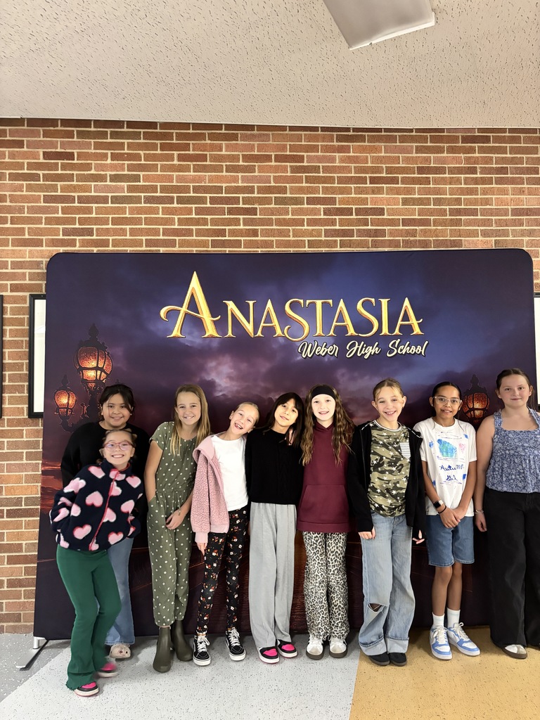 Fifth grade students in front of a banner that is advertising Weber High's school play Anastasia 