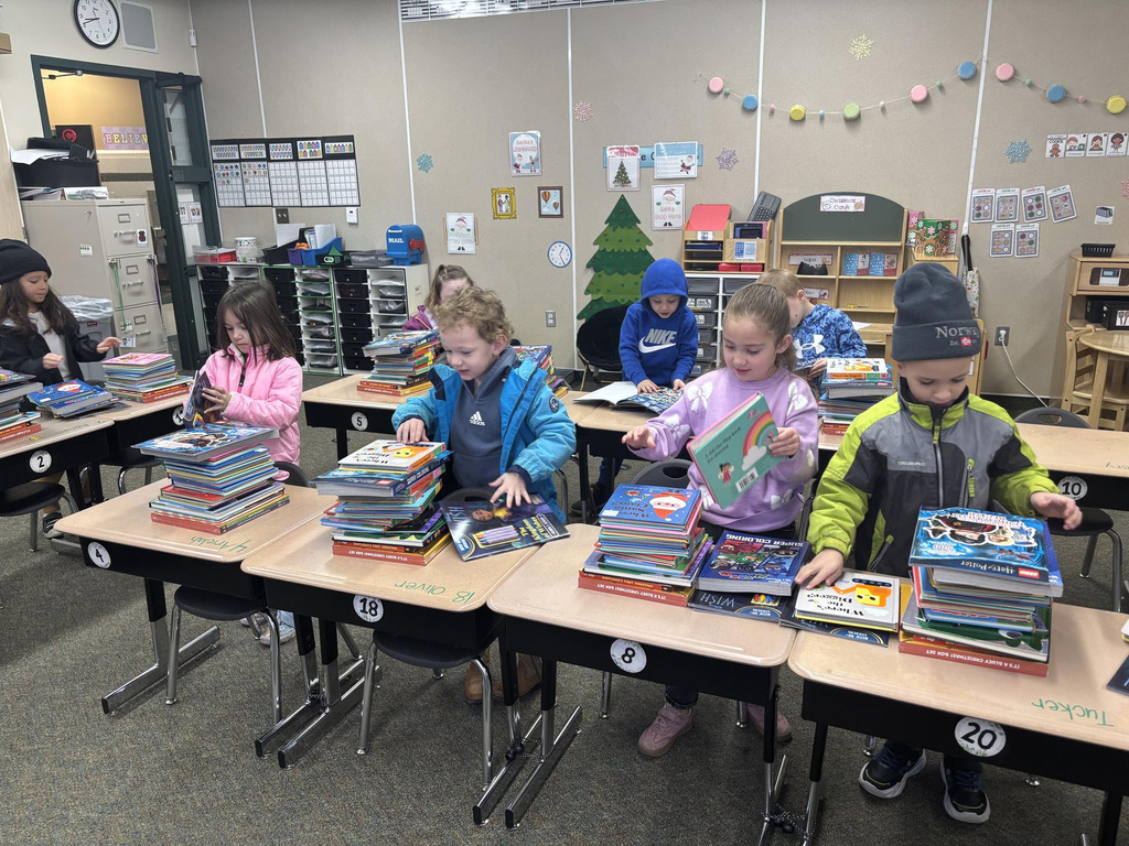 Kids looking at stacks of books they received from a secret Santa
