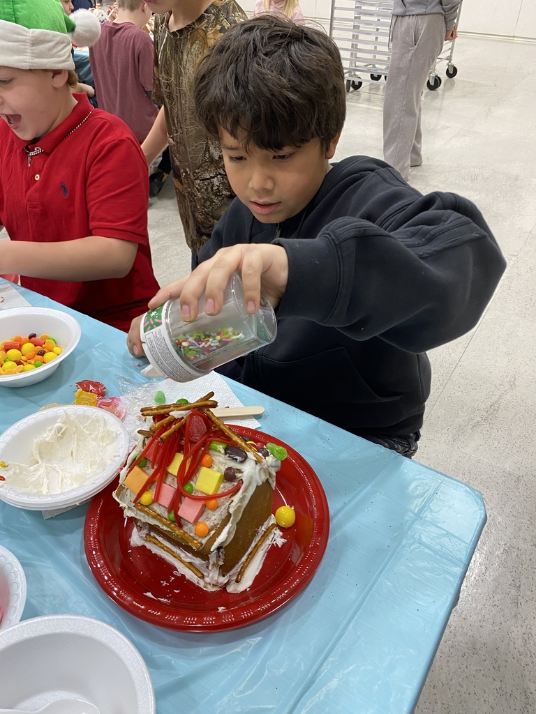 student adding sprinkles to their gingerbread house