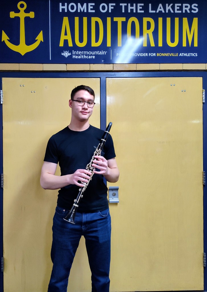 Kolbe Keller 2025-2026 All-State Band standing in fromt of the Laker Auditorium with his clarinet.