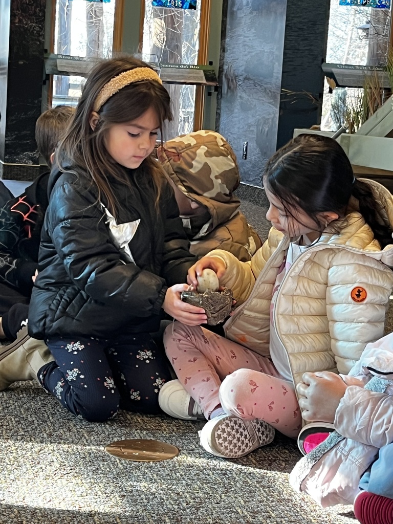 two students holding a birds nest and exploring with an egg that is in the nest