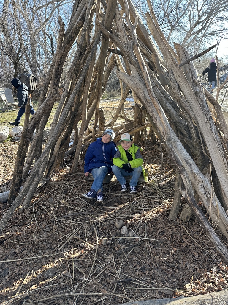 two students posing in a wooden tent