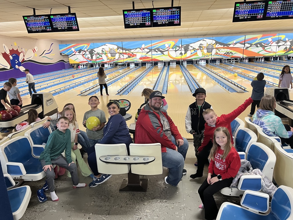 Students and parent volunteers smiling at the bowling alley.