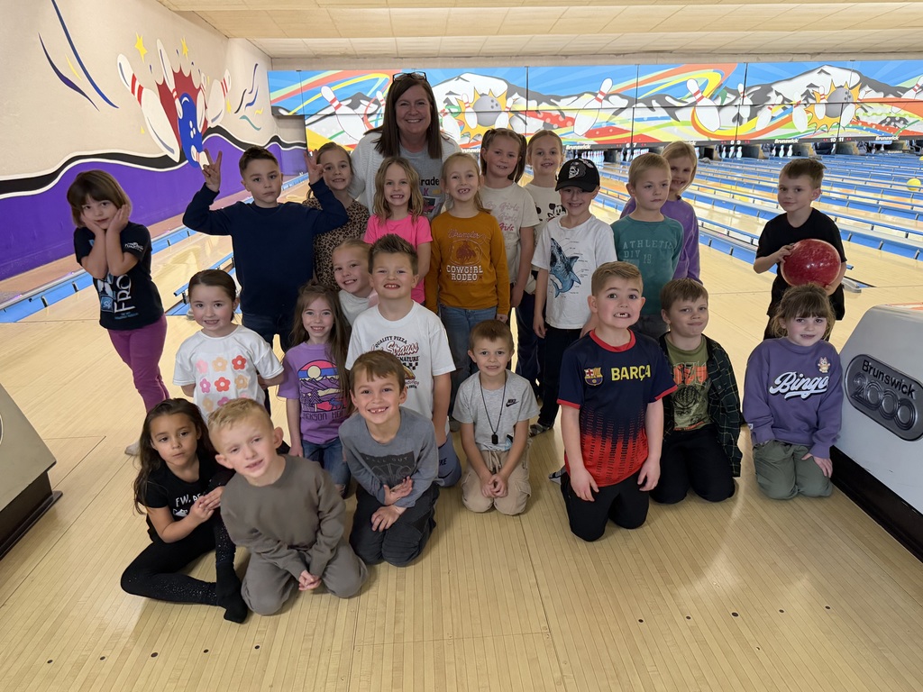 teacher smiling with students at a bowling alley