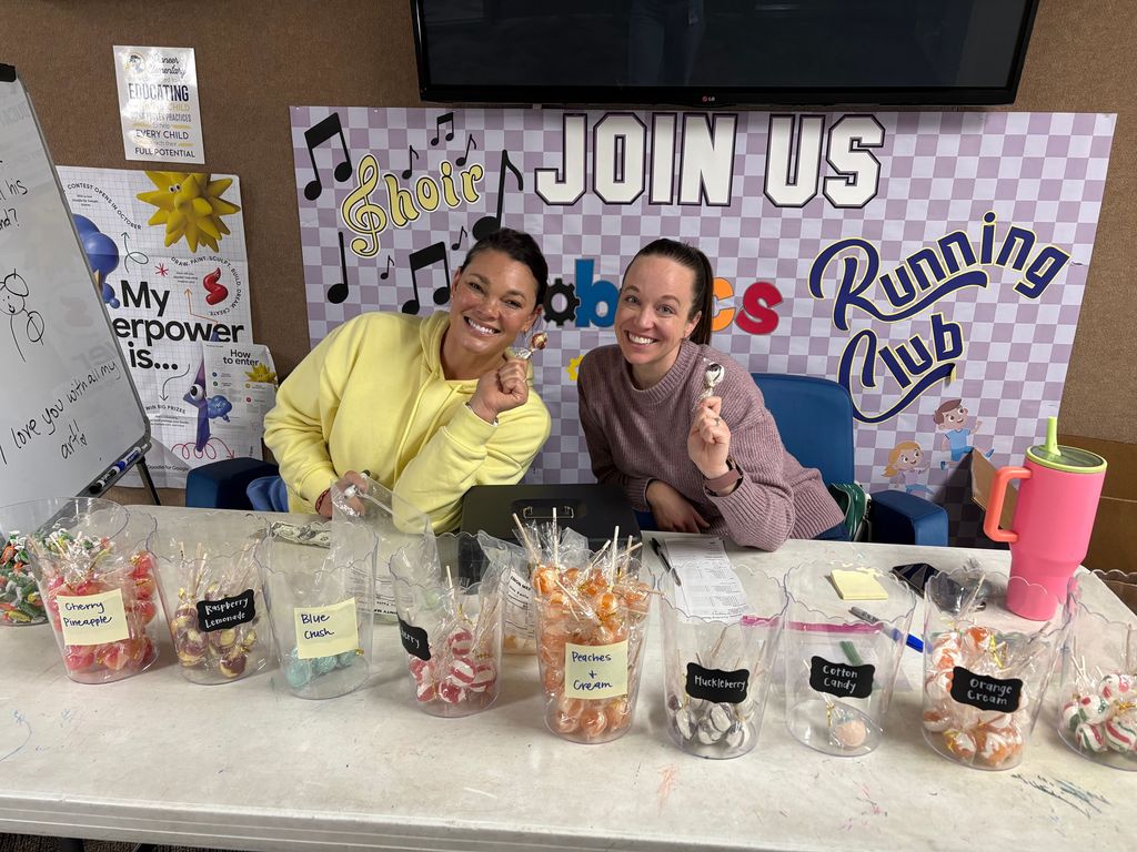 Two moms posing with suckers as they sell suckers to the students.
