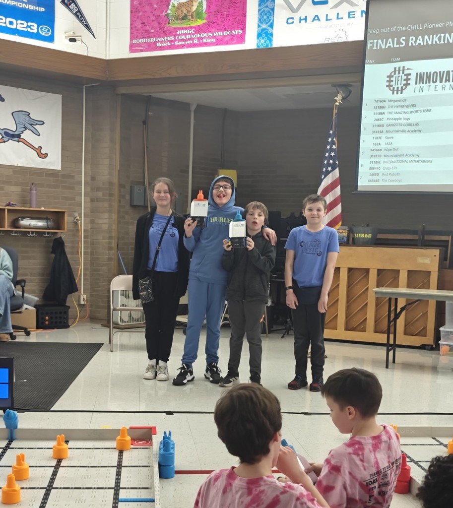 4 students standing to receive an award in a school gym. 