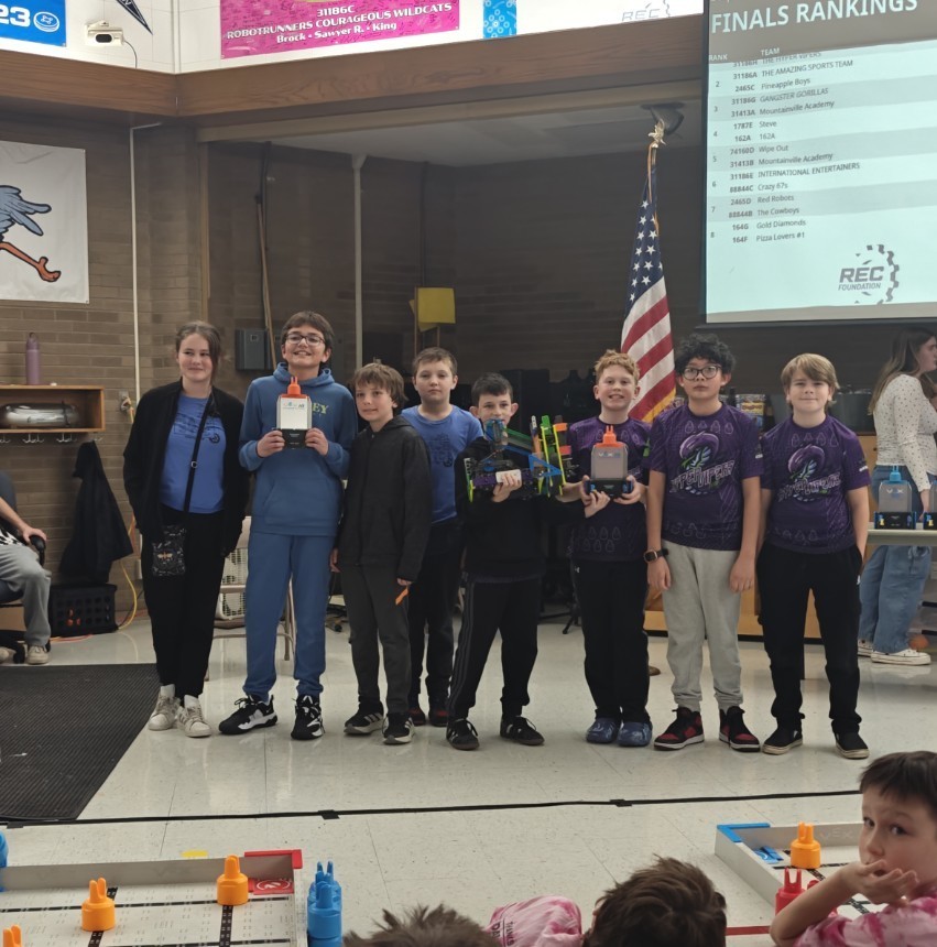 2 teams of 4 students each standing to receive an award in a school gym. 