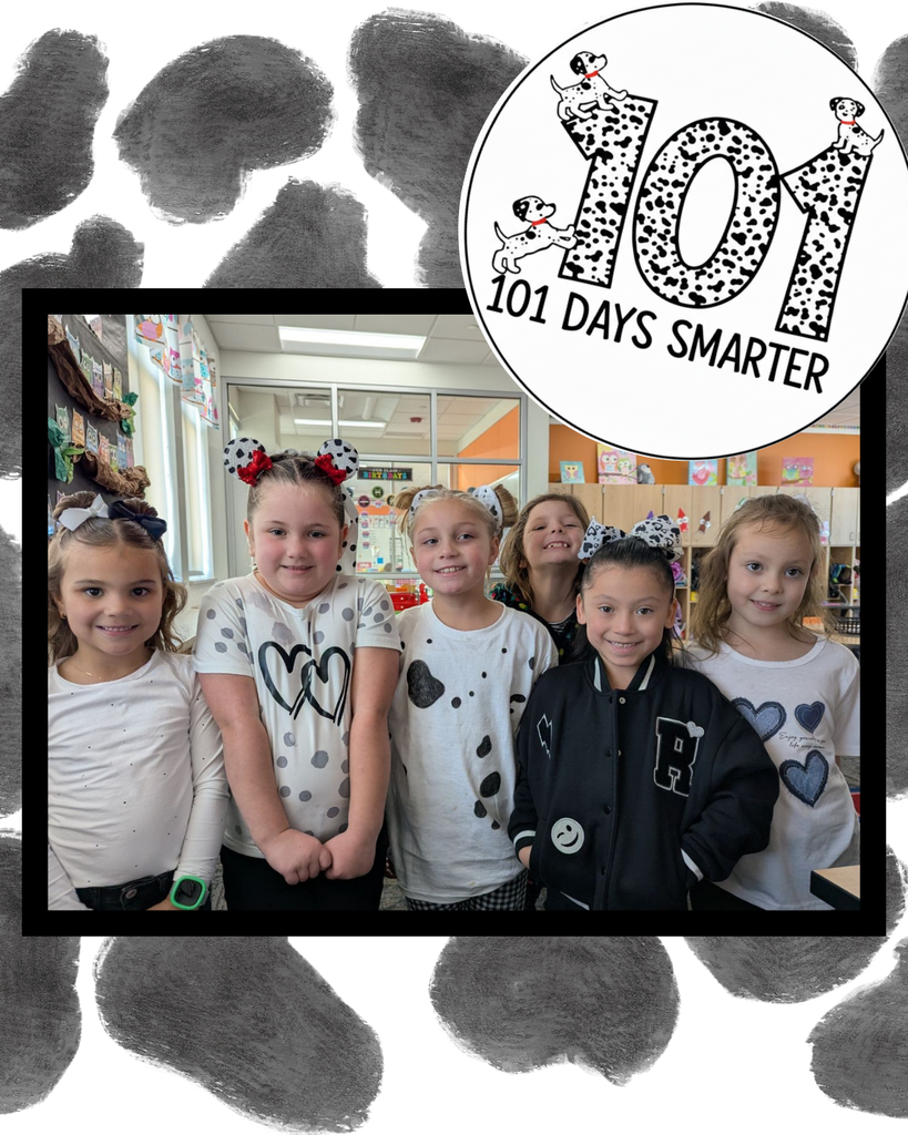 A photo of six young girls smiling and posing in a classroom. Several are wearing dalmatian-spotted shirts or hair bows with puppy ears to match the 101-day theme. The image is framed with a black-and-white spotted border and includes a circular "101 Days Smarter" logo at the top.