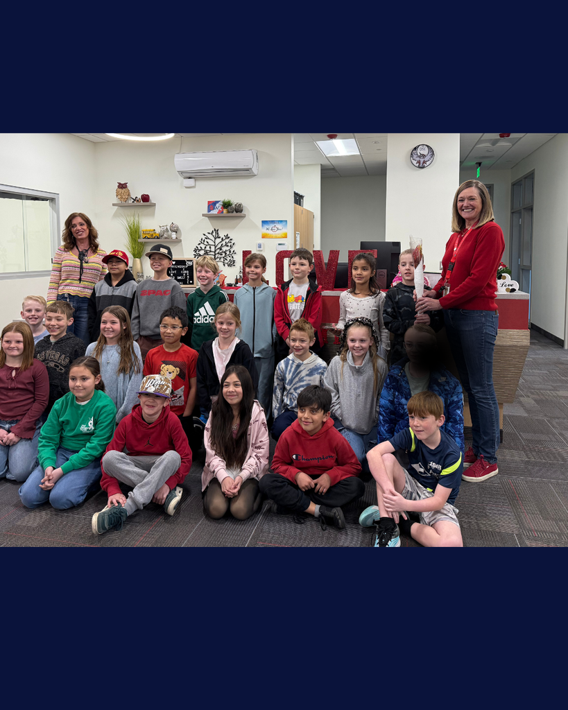Class of students smiling  with a teacher and principal holding a torch. 